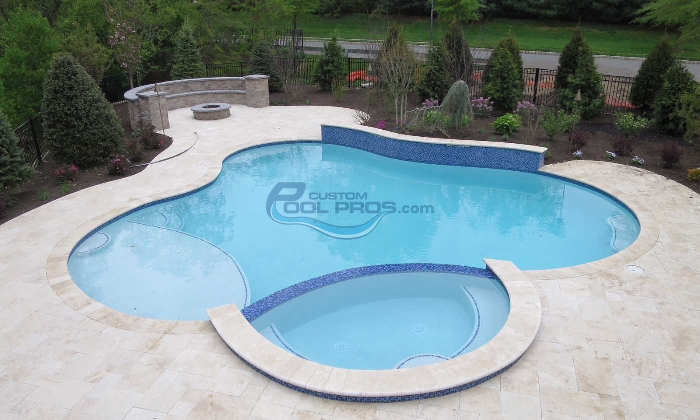 Elegant backyard swimming pool with a curved design, featuring a spa area and surrounded by lush greenery and stone landscaping. Ideal for relaxation and outdoor entertaining.