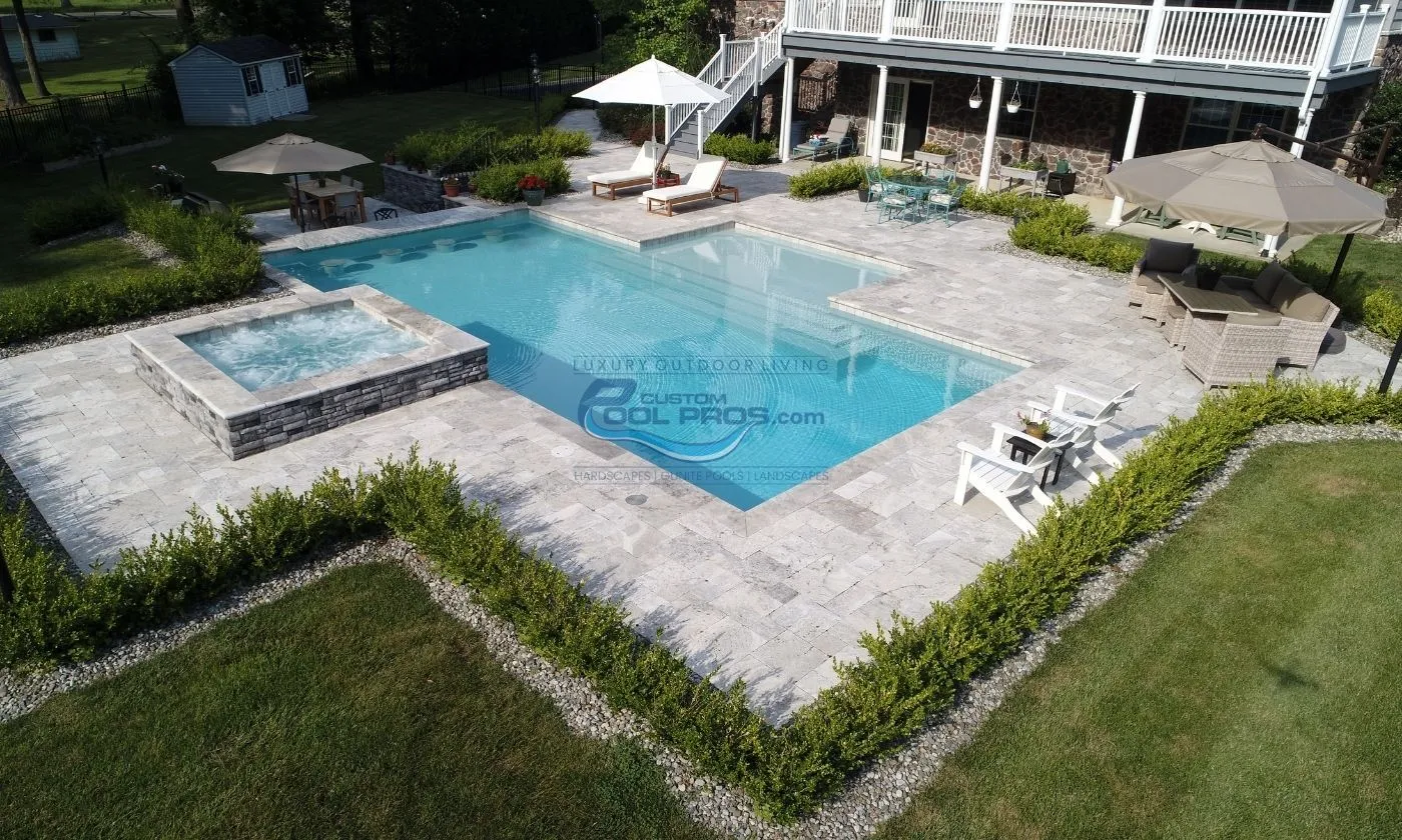 rectangular style inground pool with square raised spa and swim up bar in backyard
