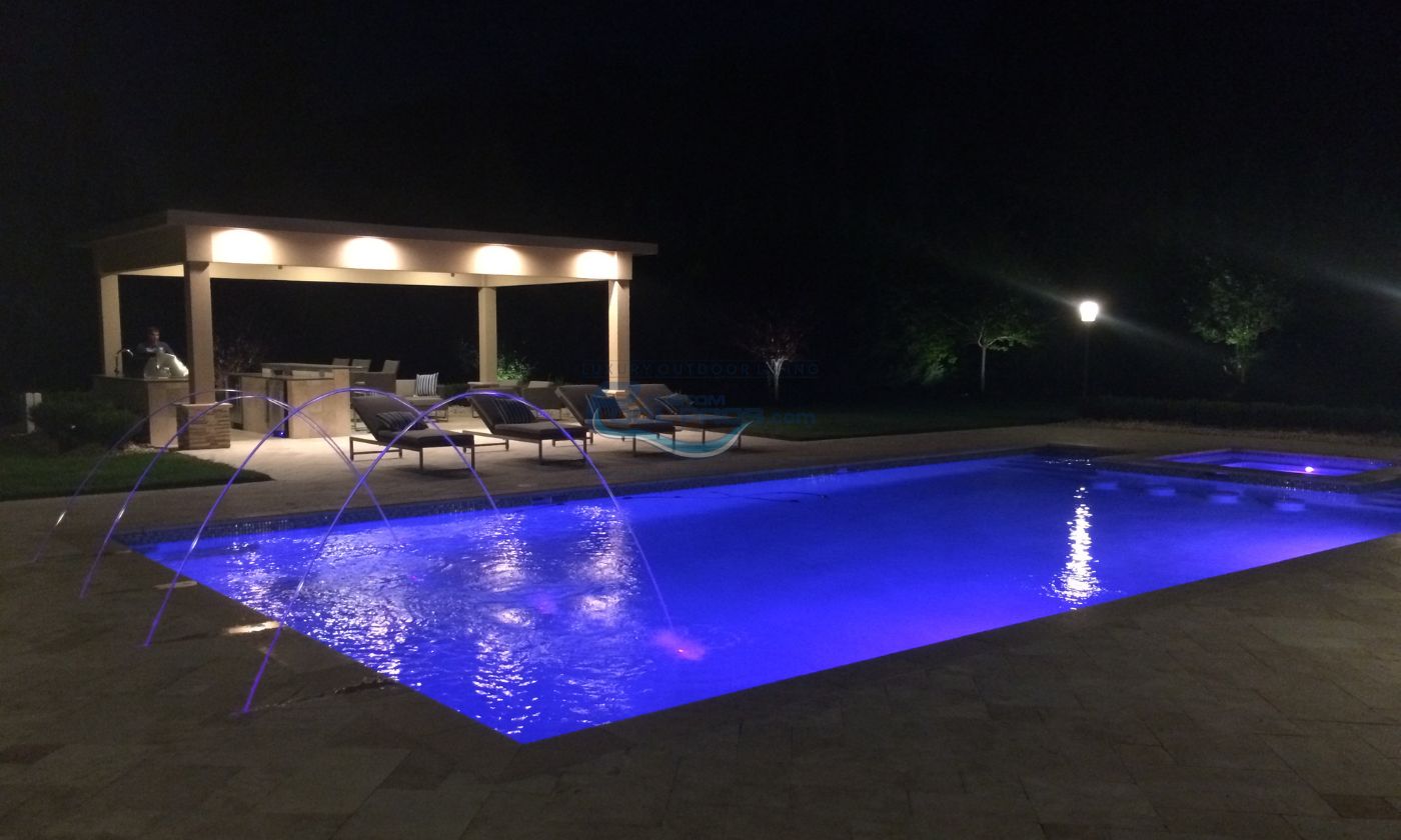 rectangular inground pool at night with pool lights, water jets and pavilion, inground pool
